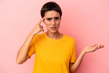 Young caucasian woman isolated on blue background holding and showing a product on hand.