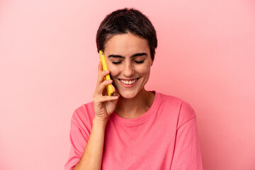 Fototapeta premium Young caucasian woman holding mobile phone isolated on pink background