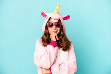 Little caucasian girl wearing a unicorn pajama isolated on pink background