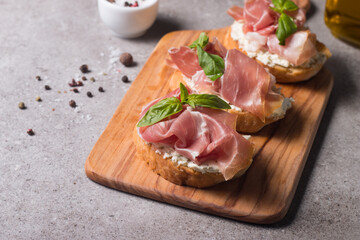 Bruschetta with prosciutto, basil, olives, spices and herbs. Appetizers.