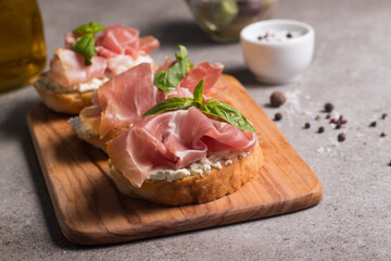 Bruschetta with prosciutto, basil, olives, spices and herbs. Appetizers.