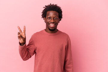 Young african american man isolated on pink background joyful and carefree showing a peace symbol...