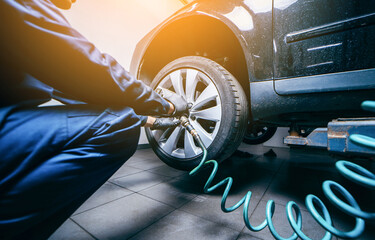 Hands of professional car mechanic changing car wheel in auto repair service. Close up   © andrew_shots