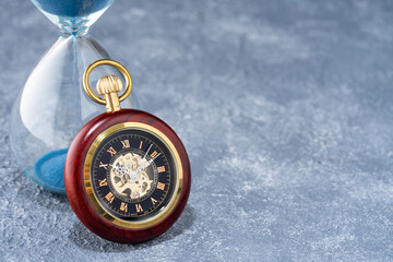 Pocket watch and hourglass on the table