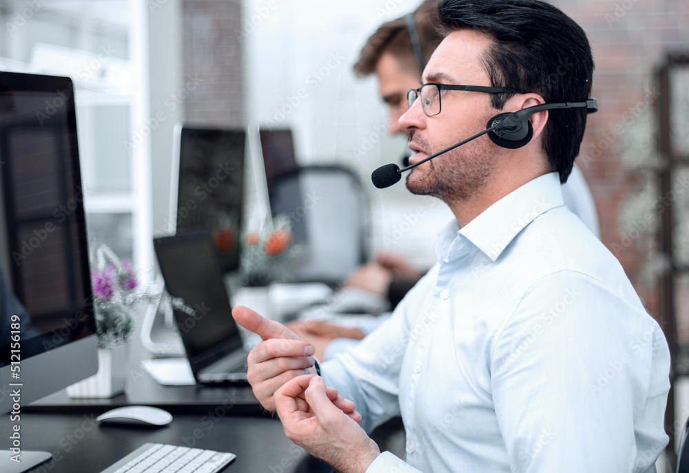 Wall mural attentive businessman in headphones sitting at the table call center.