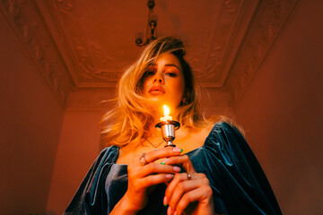Portrait of attractive caucasian woman with candlestick in the dark, vintage elegant interior.