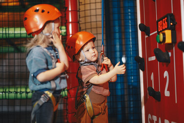 Happy School Boys in Red Helmets on Climbing Class at Indoor Climbing and Bouldering Centre. Kids Boys at Indoor Climbing Class for Kids