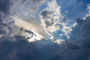 blue skylight with light among dark clouds