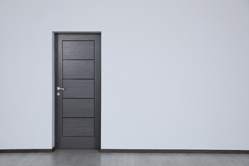 Dark wooden door in empty office, space for text. Interior design