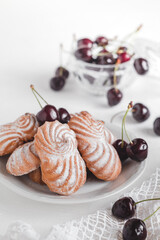 Sweet swirl shaped butter cookies on a white plate with fresh red cherry.