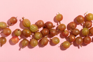 Scattered gooseberries on a pink background.