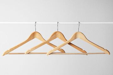 Wooden clothes hangers on metal rail against light grey background