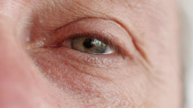 Eye care. Vision correction. Ophthalmology treatment. Macro of tired sad depressed senior man face with wrinkled eyelid skin gray iris.