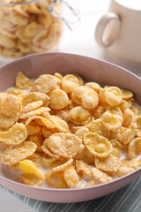 Tasty cornflakes with milk in bowl on table, closeup