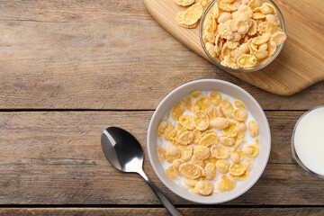 Tasty cornflakes with milk served on wooden table, flat lay. Space for text