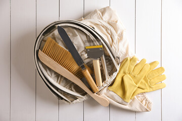 Different beekeeping tools on white wooden table, flat lay