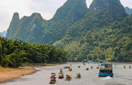 Set of boats sailing the li river in china with a landscape full of majestic chinese mountains in the background