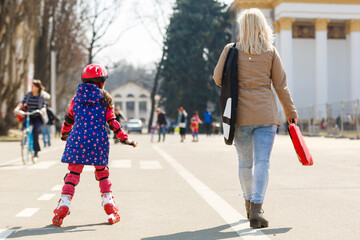 Caucasian woman teaches her daughter to skate on roller skates