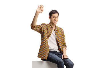 Young man sitting on a white column and waving