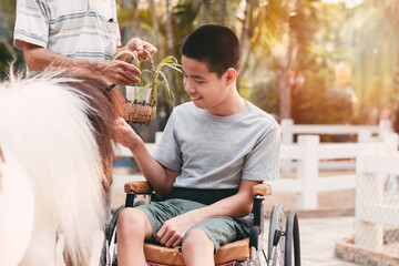 Teenager boy with a disability feeding pets with smile and happy face, Training of muscles through...