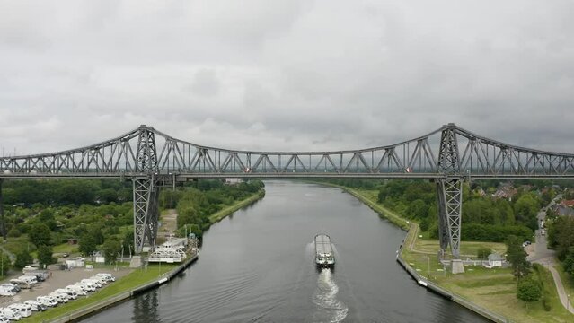 Cargo ship (freighter) passing Rendsburg High Bridge (Rendsburger Hochbr&uuml;cke) over Kiel Canal (Schleswig-holstein)