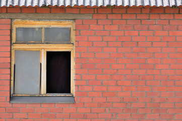 Old aged shed broken window glass, red bricks hut wall background, weathered grungy rusty dirty damaged wooden frame, textured large detailed horizontal shack backdrop, blank empty copy space closeup