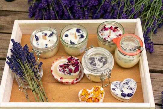 Selbstgemachte Kerzen mit Lavendel und Bl&uuml;ten auf Tablett