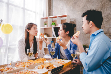 Bravo! A group of cheerful young people enjoy food and drink together in the office.