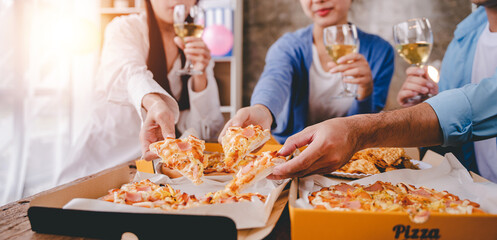 hands of a colleague or friend eating pizza After meeting at the office for a long time They're partying at home, eating pizza and having fun. food and drink people and holidays