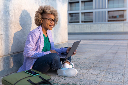 Confident modern business African American woman with laptop outside the office in the city. Creative professional working outside. High quality photo