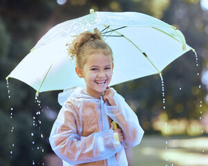 Time to get up to some mischief. Shot of a little girl playfully standing in the rain holding her...