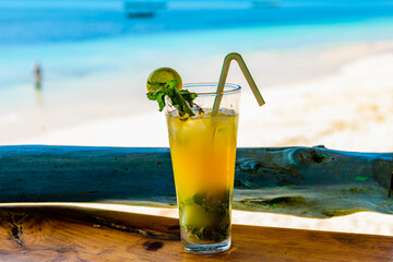 Glass of orange mojito cocktail. Ocean at the background
