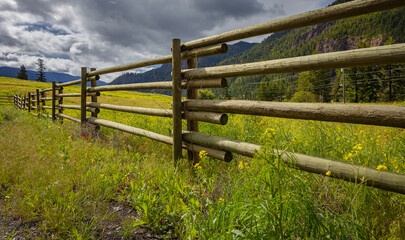 Typical wooden fence in farmland. Country Farm with brown fence in overcast summer day.