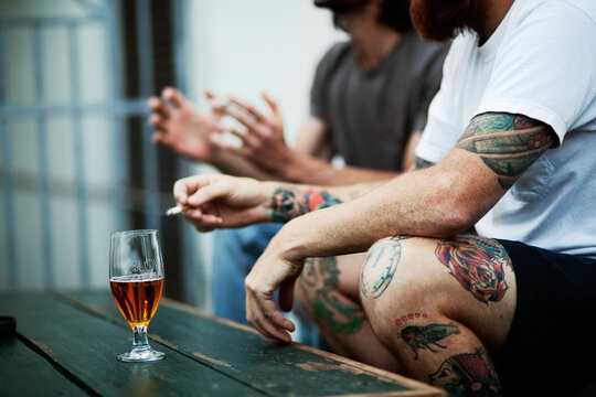 Summer time socializing. Shot of young people smoking and drinking.