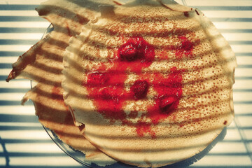 fried pancakes are on a plate, strawberry jam is on top