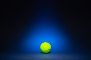 Yellow tennis ball on blue background.