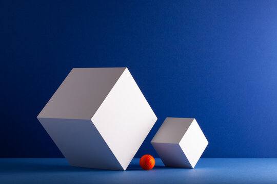 Two cubes with orange golf ball on the blue background.