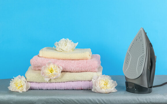 Electric Iron, Ironed Linen And Flowers On A Blue Background.