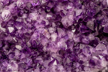Amethyst purple crystals. Gems. Mineral crystals in the natural environment. Texture of precious and semiprecious stones. Seamless background with copy space colored shiny surface of precious stones.