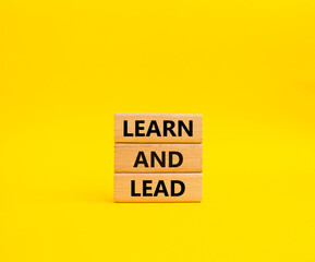 Learn and lead symbol. Concept words 'Learn and lead' on wooden blocks. Beautiful yellow background. Business and Learn and lead concept. Copy space.