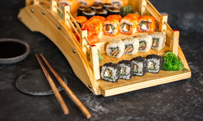 Sushi rolls Japanese delicacies. Japanese traditional rice and fish dishes. Beautiful serving food on a dark background with copy space. A set of delicious goodies.
