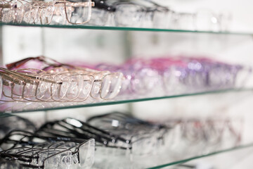 Sunglasses on the shelves of optics. Large selection of points. Points laid out on the glass shelves of the store in neon lighting.