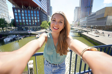 Beautiful young woman taking self portrait with Rotterdam cityscape on the background, Netherlands