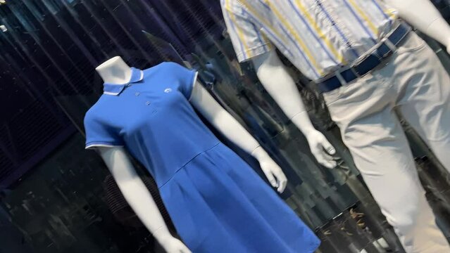 Female and male mannequins (dummy) stand in the window of a clothing store or boutique. Dutch angle