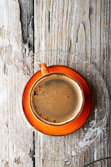 fresh boiled coffee served in beautiful prange cup around old style wooden background . close up. flat lay