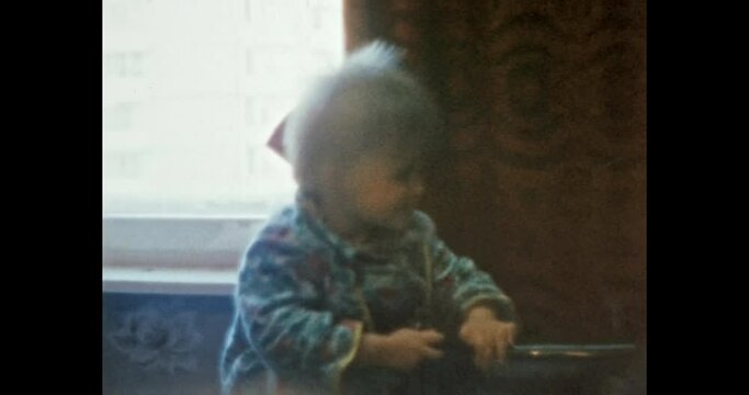Funny little child playing with sewing machine in room. Baby girl smiles, explore world. Active, curious kid having fun. Happy family life indoors. Vintage color film. Family archive. Retro 1980s. 4k