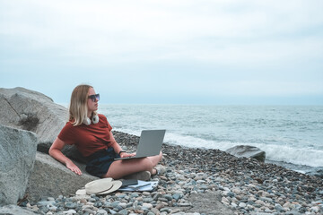 Remote work.Girl freelancer works remotely on the seashore.workation, remote work,WFVH,Van Life vibes work from vacation home,work travel,remotely work.Travelling