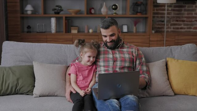Father and daughter watching funny videos, browsing online tv on laptop with smile face. Happy family rest on coach with computer, enjoy spending time together on weekend at home. Father day.
