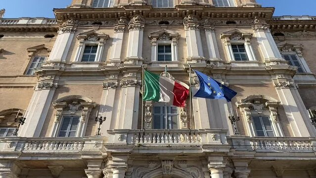 Italian and European flags waving in the wind of the facade of goverment palace
