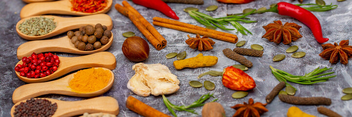 A set of spices on a gray background. Variety of spices from India. Food decoration design. Various spices, peppers and herbs close-up top view. Set of peppers, salt, herbs and spices for cooking.